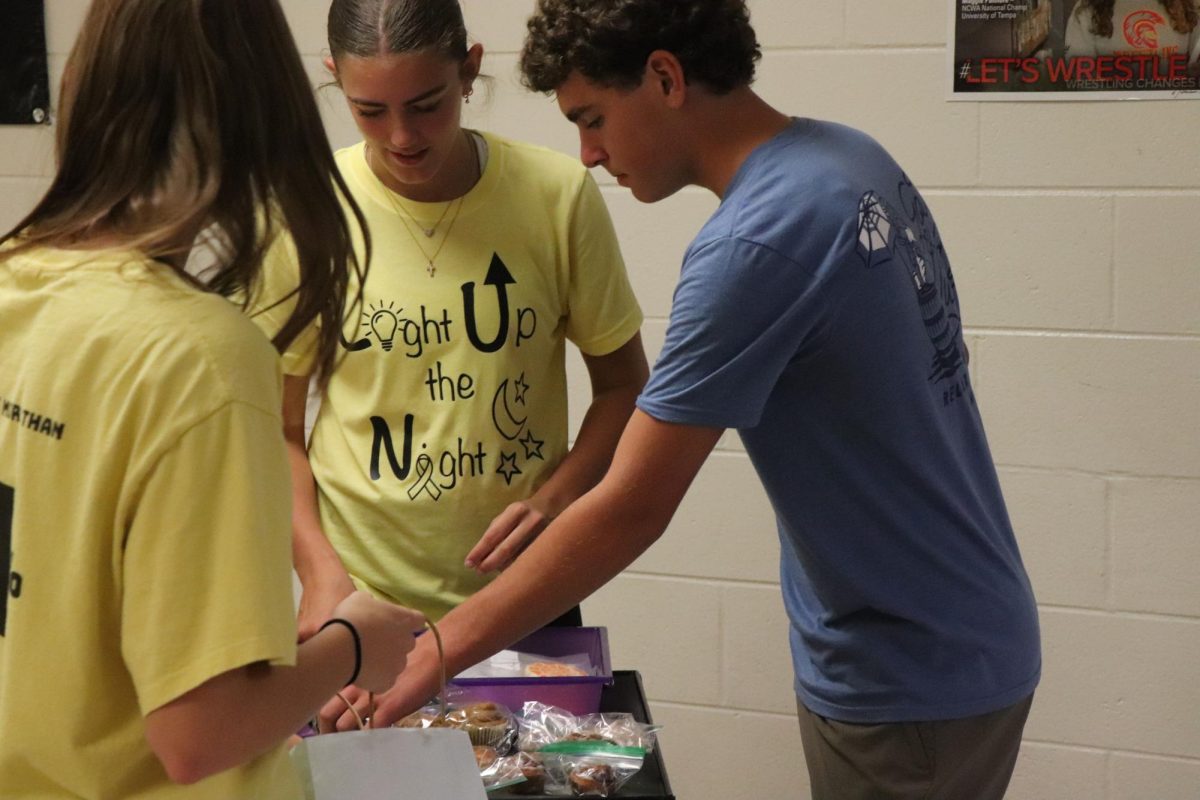 Selling baked goods, Junior Eva Long sells treats to raise money for childhood cancer. On Sept 18 the volleyball team went class to class selling goods in order to raise money and awareness for childhood cancer.