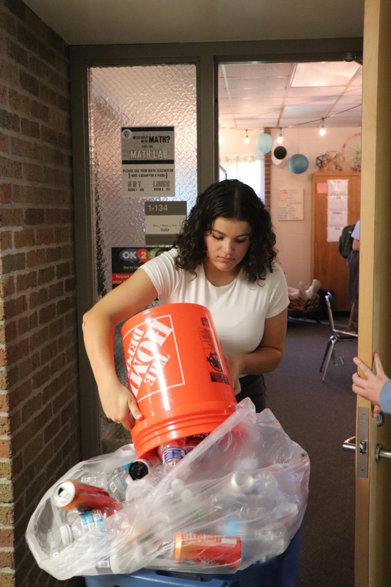 Dumping cans into the recycling bin, senior Anna Logan volunteers her time to the school. On Sept. 10, students helped to collect cans during SRT for E.C.O. Club. 