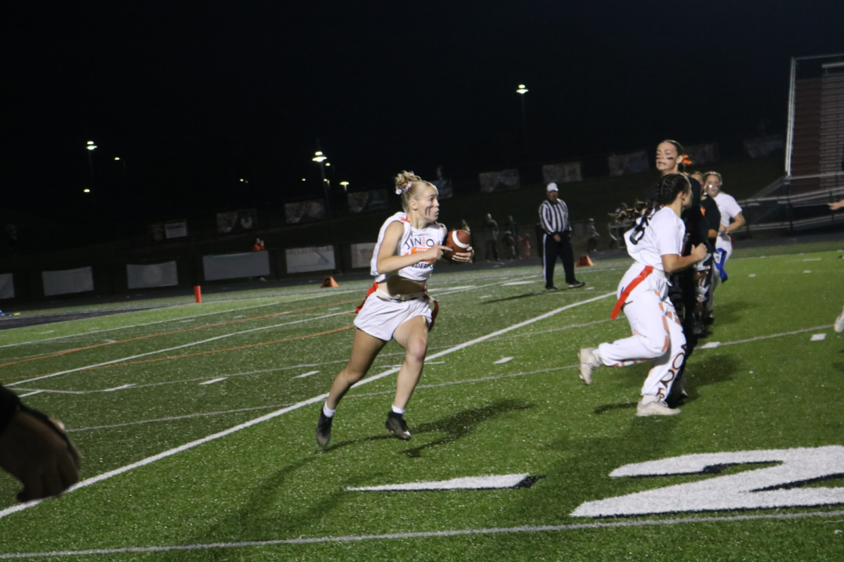 Running the ball, junior Reese Canada plays running back in the FHS powderpuff game. On Sept. 23, Fenton High held their annual powderpuff game and the seniors won 27-12.