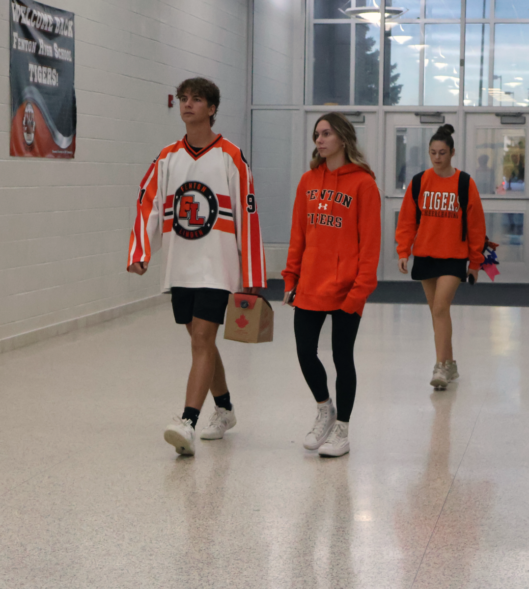 Walking into school, seniors Luke Rittenger and Ella Brzezinski show their school spirit by wearing orange and black. On Friday, Sept. 27, students wore orange and black for homecoming.