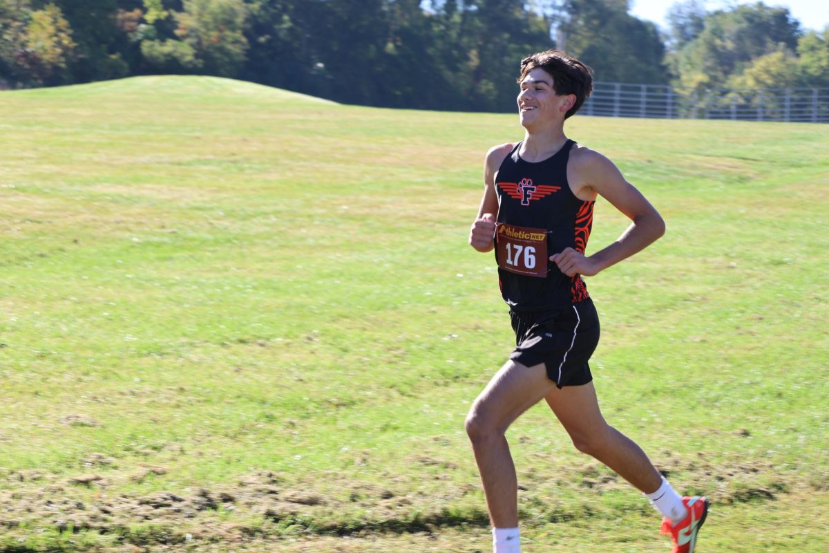 Smiling, freshman Luke Battaglia races at the greater flint championship. On Oct. 5th Battaglia placed 7th with an astounding race helping the tigers got 2nd in the meet.