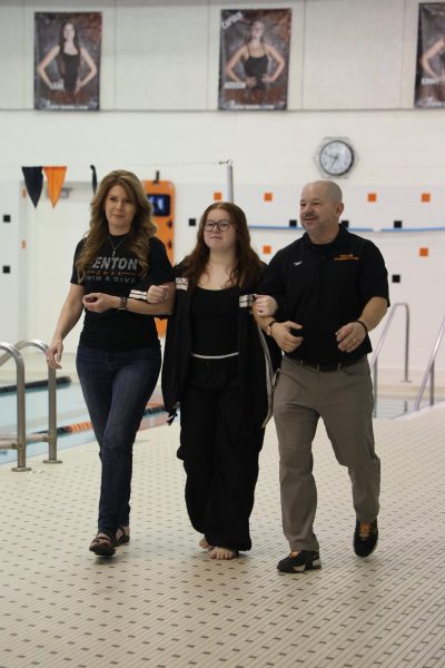 Linking arms, senior Hannah Jones walks across the deck with her parents Coach Brad Jones and Dana Jones. On Oct. 17, the FHS Swim and Dive Team held a senior night for last year  seniors.