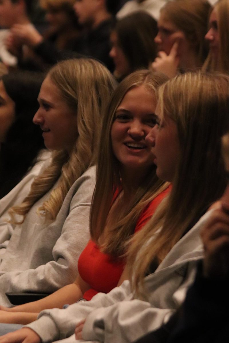 Smiling, freshman Camryn Underwood watches the guest speaker. On Oct. 17, a mental health presentation took place in the auditorium. 