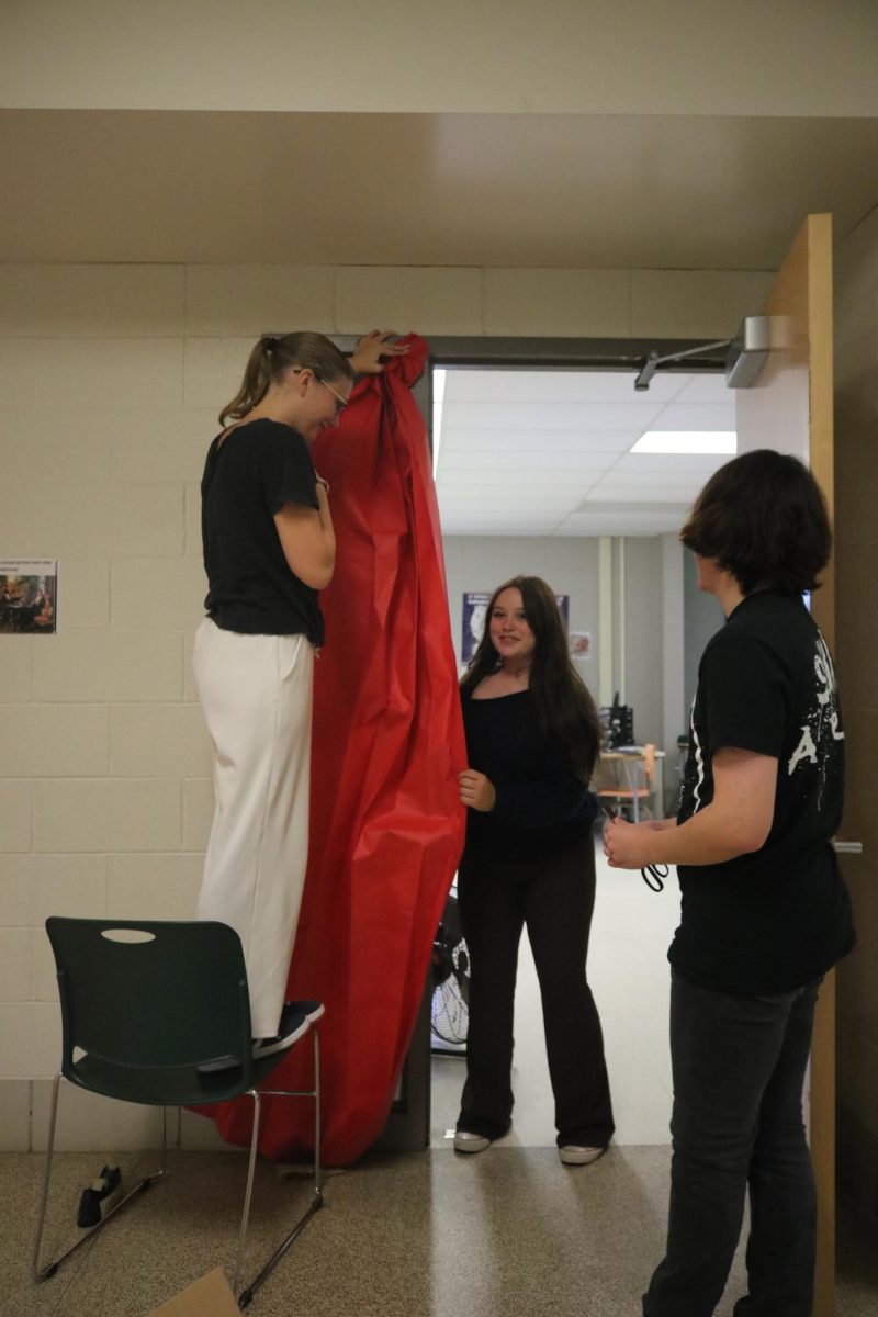 Helping, senior Brook Waters participates in door decorating for homecoming. On Sept. 10, students designed their doors in SRT. 