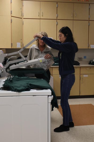 Pressing, junior Kess Vosburgh helps classroom aide Marcia Verscheure make shirts for the Fentonian Staff. On Oct. 17, Tiger Ink helps out the 2025 Fentonian by making their staff shirts.