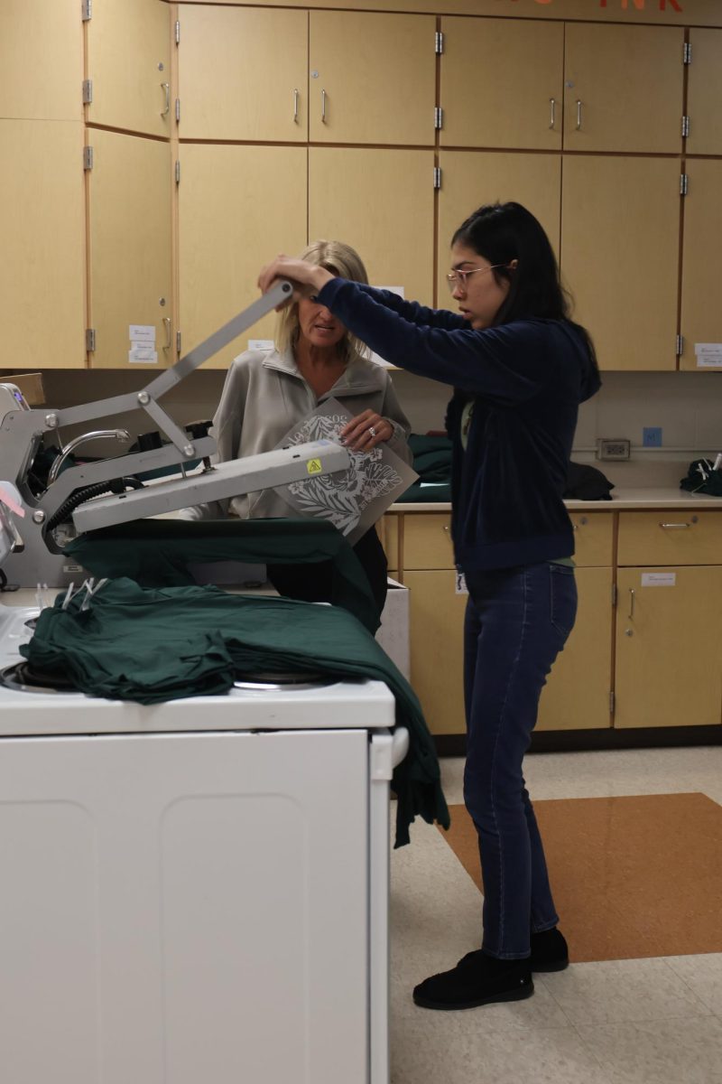 Pressing, junior Kess Vosburgh helps classroom aide Marcia Verscheure make shirts for the Fentonian Staff. On Oct. 17, Tiger Ink helps out the 2025 Fentonian by making their staff shirts.