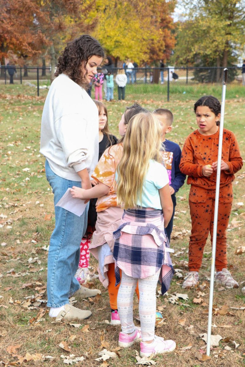 Talking to elementary students, senior Anna Logan explains the activity at her station. On Oct. 23, FHS students helped out at pond day, where students from Tomek, North Road, and State Road visited the FHS pond.