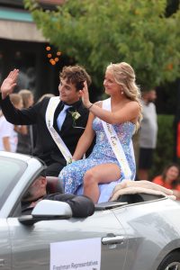 Waving, freshmen Lucas Christopher and Lucy Britton ride in a car. On Sept. 27, Fenton held their annual homecoming parade.