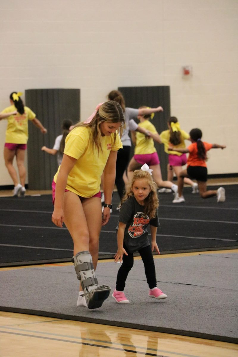 Stretching, senior Kimberly Burkett participates with her team. On Oct. 16, the cheer team hosts a kids clinic for  the youth cheerleaders in the auxiliary gym.