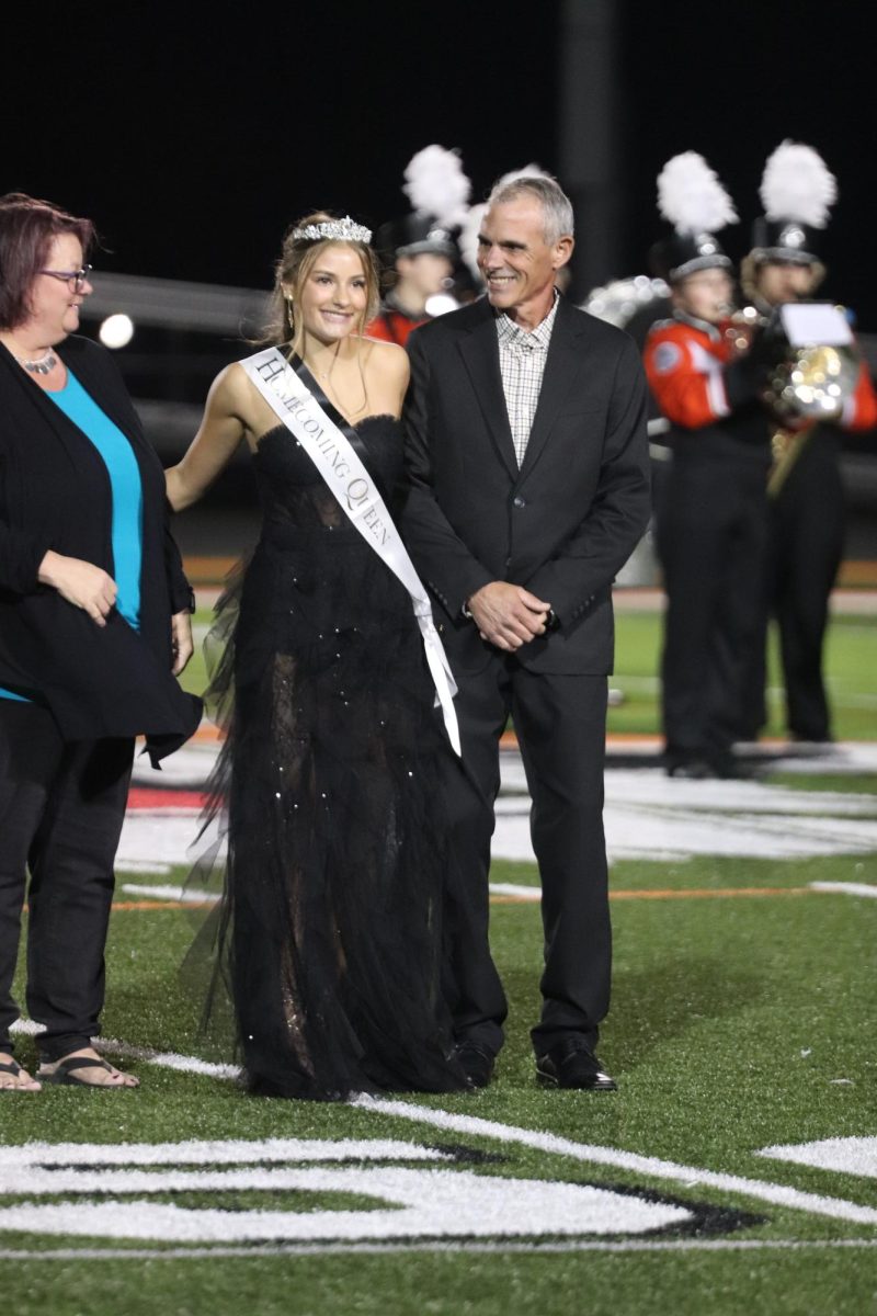 Smiling, senior Paige Lefever stands with her parents. On Sept. 27, Lefever was crowned Homecoming Queen.