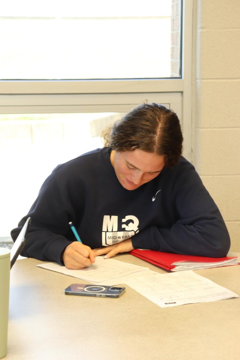 Writing, senior Megan Gornick does her homework. On Oct. 4, online classes took place in the media center.