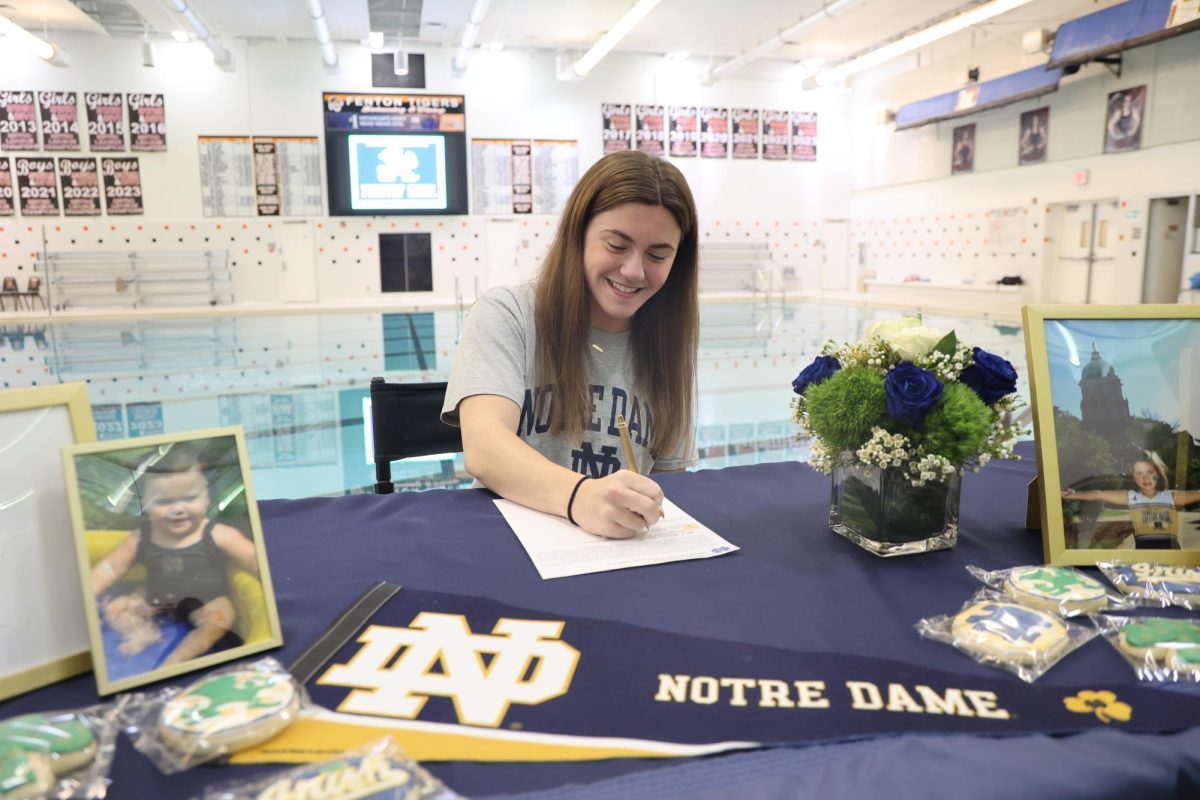 Writing her signature, senior Tess Heavner commits to Notre Dame. On Nov. 13, a signing off celebration was held on the pool deck. 