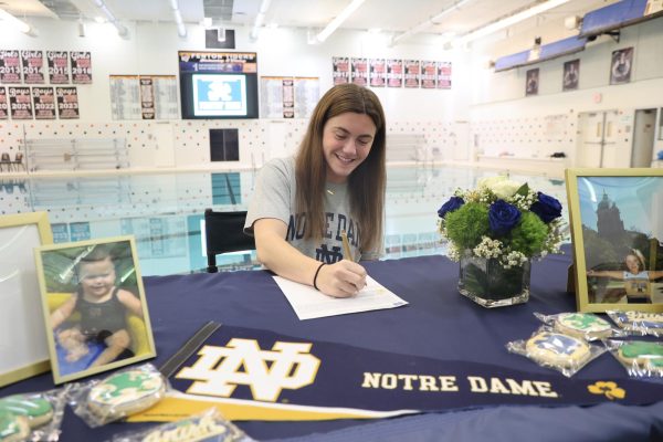 Writing her signature, senior Tess Heavner commits to Notre Dame. On Nov. 13, a signing off celebration was held on the pool deck. 