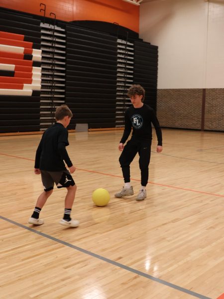 Dribbling the ball, sophomore Trenton Rockman plays soccer with a little kid. On Nov. 8, the Fenton Varsity Griffins held their annual hockey lock in for kids grades 3rd through 6th.