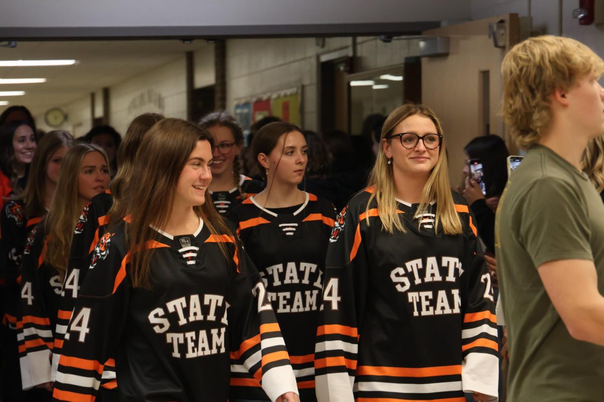 Smiling, senior Addison Dolliver and Tess Heavner participate in the swim state qualifying walk out. On Nov. 21, the girls swim teams state qualifiers had a walk out to celebrate their accomplishments.