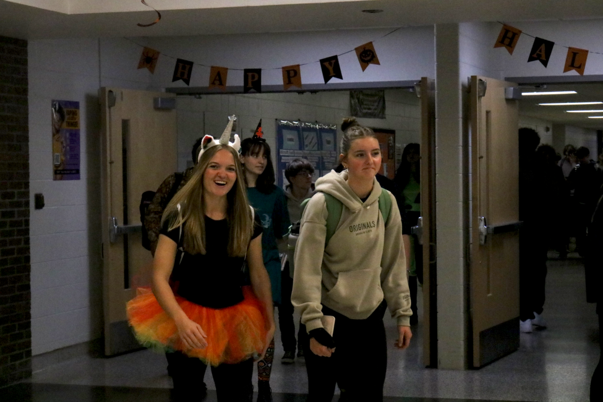 Smiling, Camryn Underwood and Clare Sturgis walk through the square wearing a halloween costume. On Oct. 31, The school held a halloween costume dress up day.