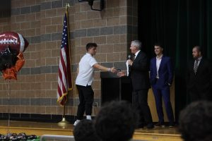 Shaking Hands, Junior Nate Fuller shakes his varsity head coaches hand  at the Football banquet. On Nov, 20 the football team held their end of the season banquet.