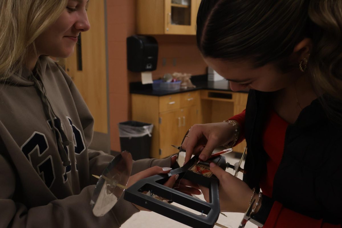 Constructing, sophomores Addie Coleman and Gaia Watson build their mousetrap car. On Dec. 9th Mr Jeffery's Physics class did a mouse trap lab.