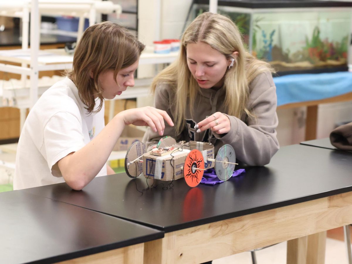 Creating, Sophomore Addie Coleman works on her mouse trap car with her lab partner Senior Maddie Sheffield. On Dec 9, Mr.Jeffery's physics class made mousetrap cars.