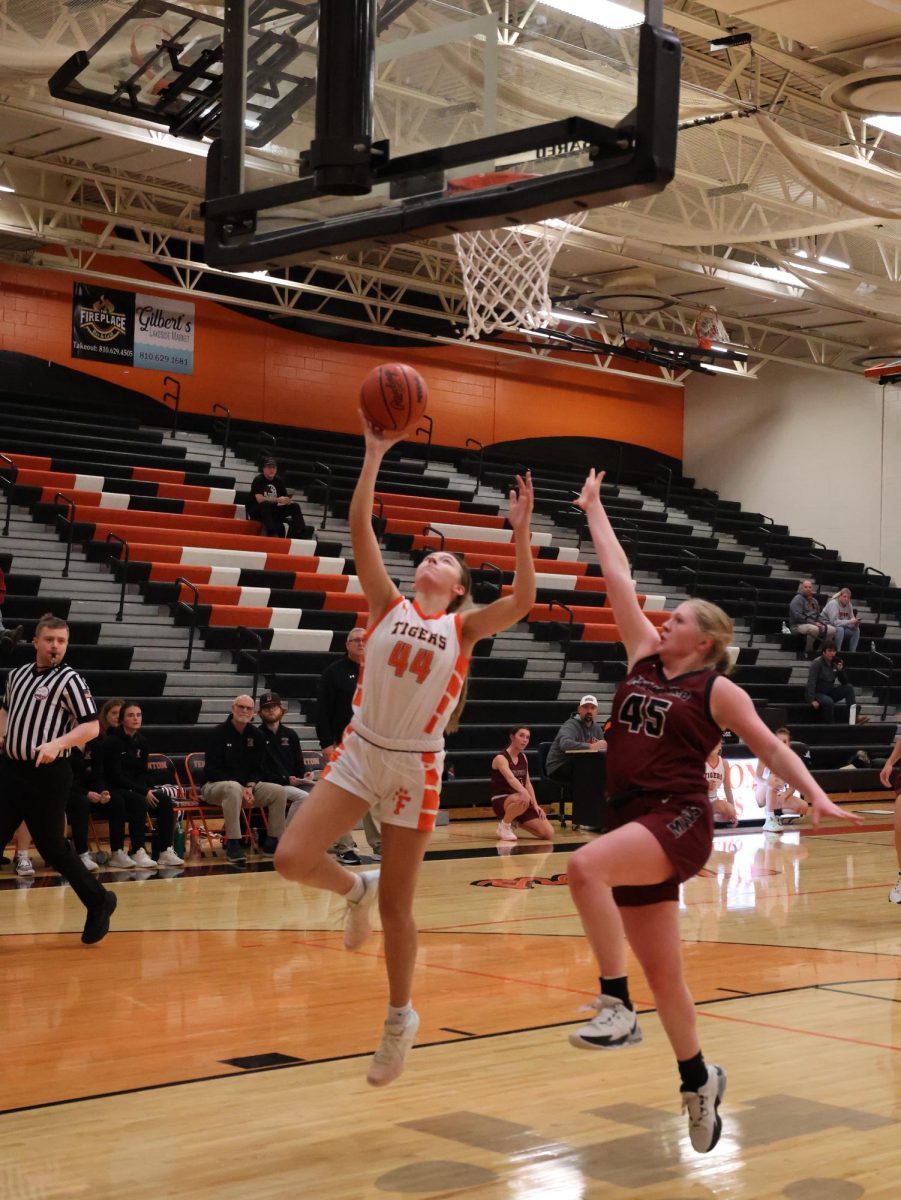 Jumping, sophomore Lucy Webber attempts to shoot. On Dec. 10, the girls Varsity basketball team went up against Milford.