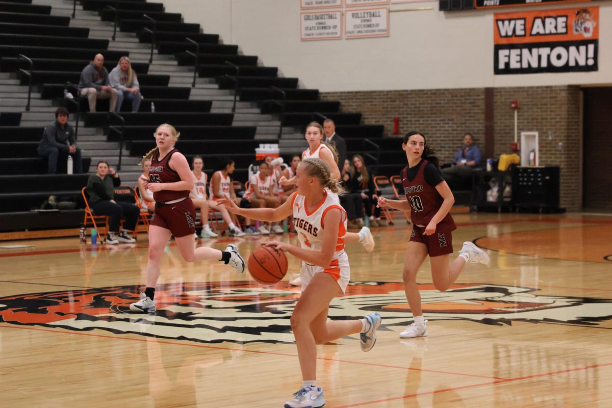 Playing, senior Izzy MacCaughan dribbles the ball along the court. On Dec. 10, the girls Varsity basketball had a game against Milford High.