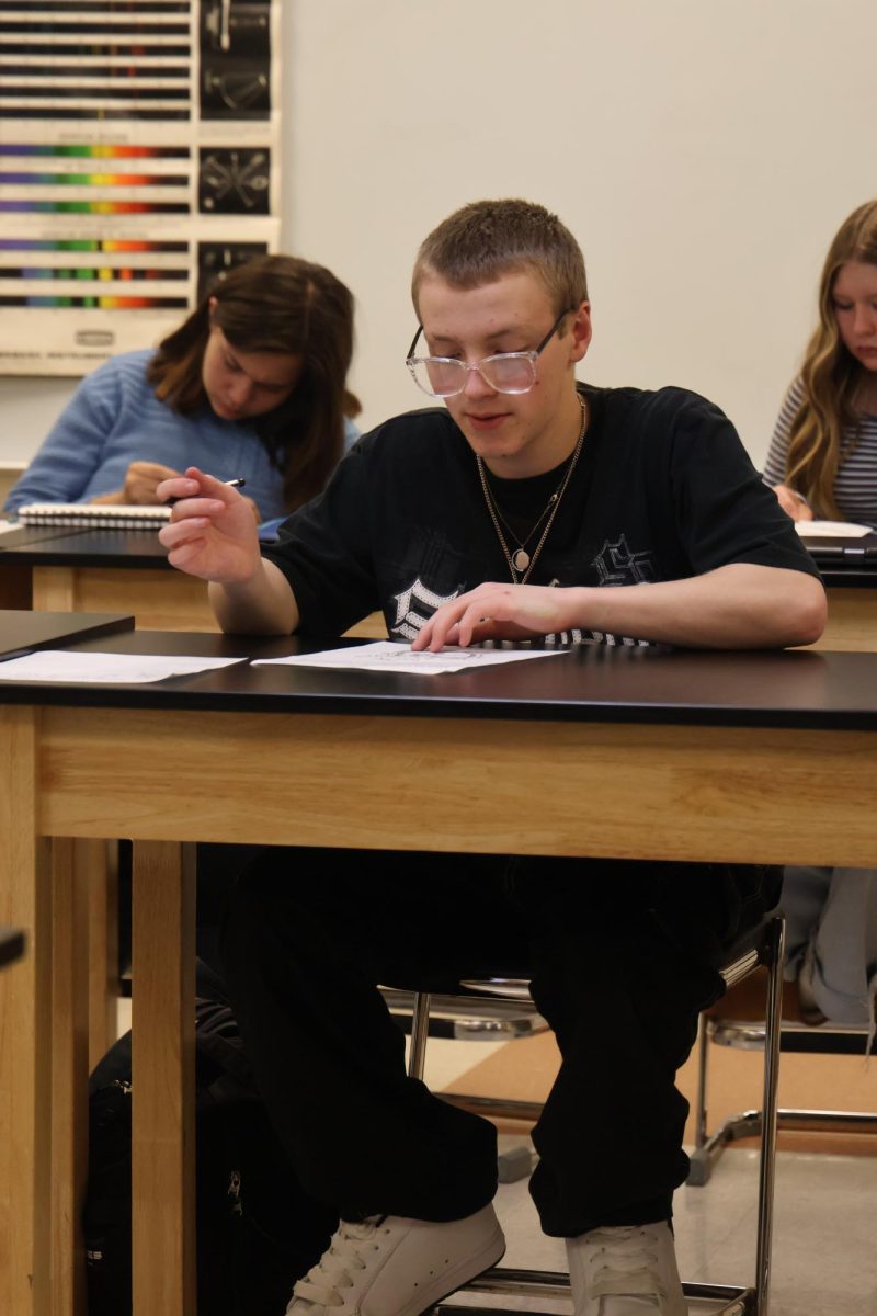 Reading the instructions, freshman Christopher Spencer learns about the heart. On Dec. 9, Mr. Jeffrey's biology class draws and labels parts of the heart.