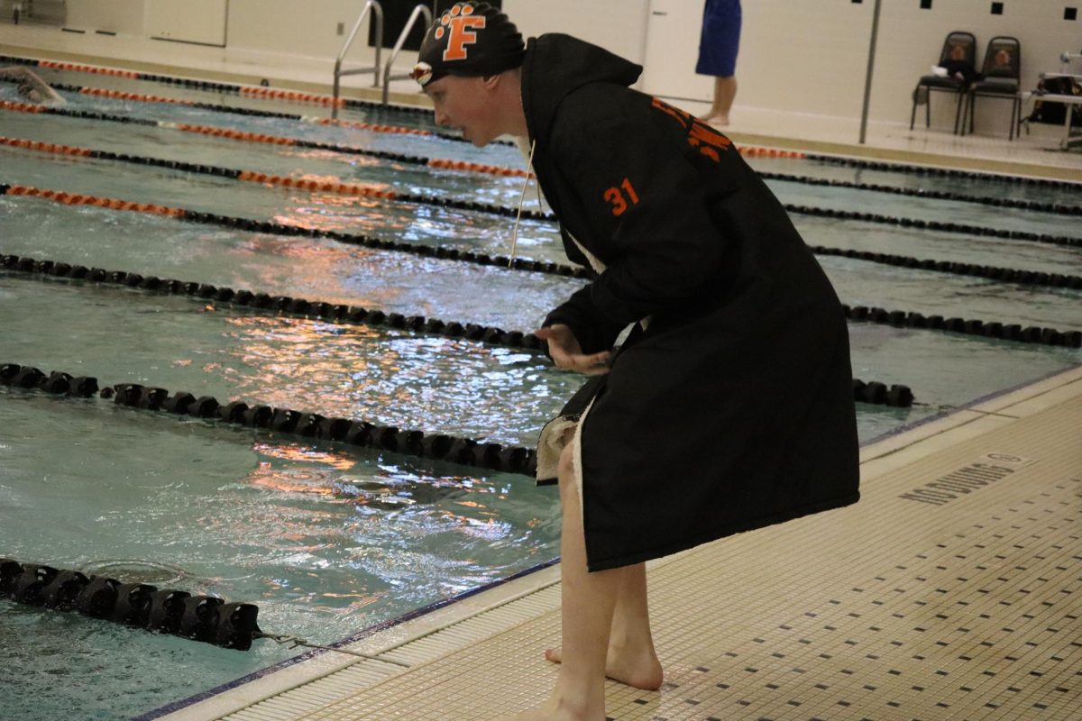 Cheering, junior Michael Ferris encourages his teammate. On Dec. 19, the boys varsity swim team kicked off the season. 
