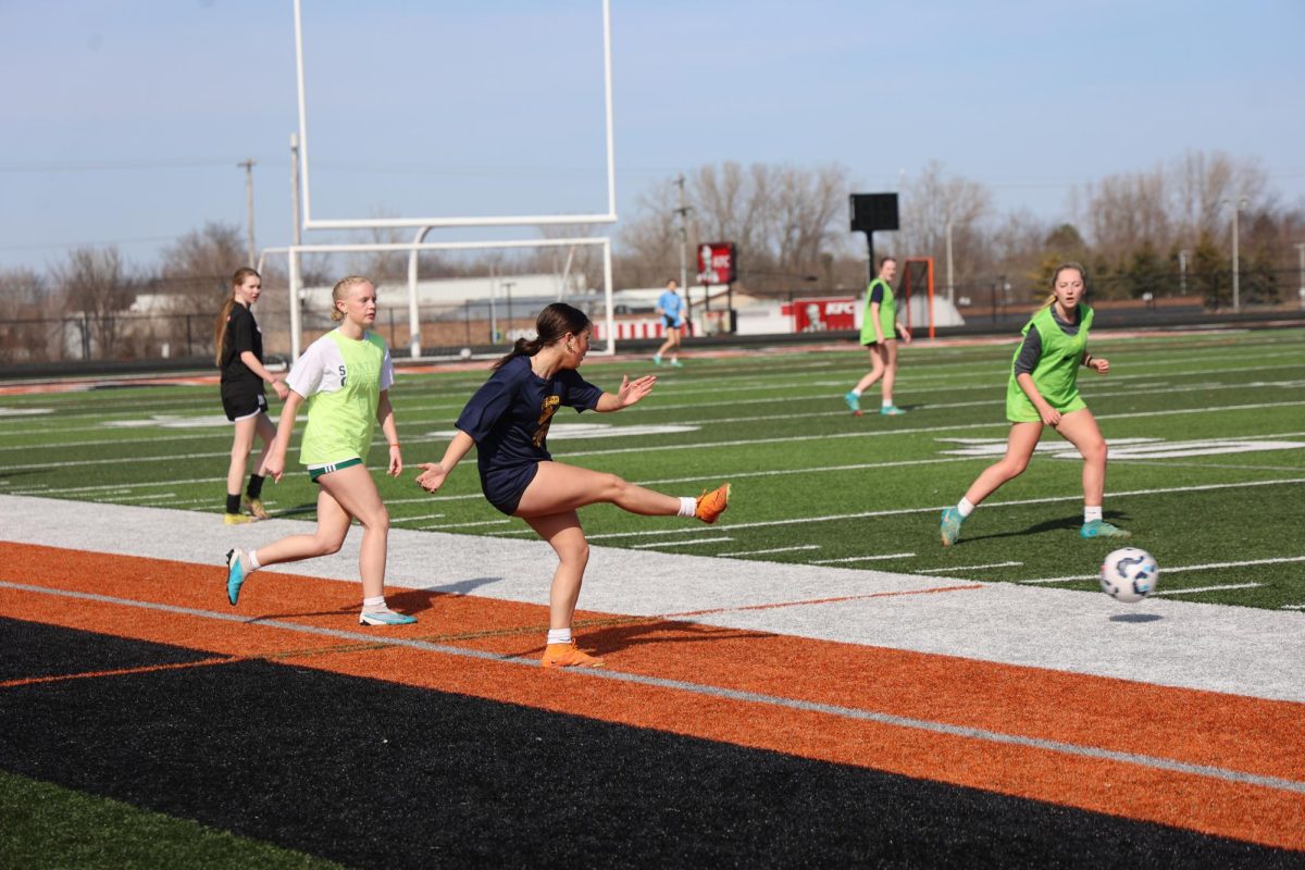 Kicking, sophomore Peyton Kelso passes the ball.  On March, 11.  the girl's soccer team had tryouts.