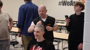 Razor in hands, Coach Brad Jones shaves his swimmers head. On Feb. 27, members of the swim team participated in a tradition before states. 