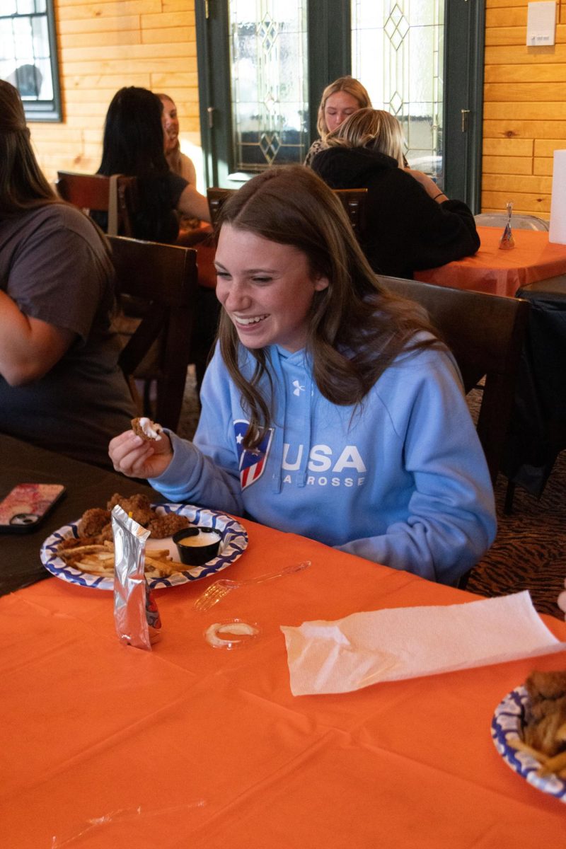 Laughing, junior Eliana Carr chats with her teammates. On Apr. 14, the Fenton girls' varsity lacrosse team held a team bonding. 