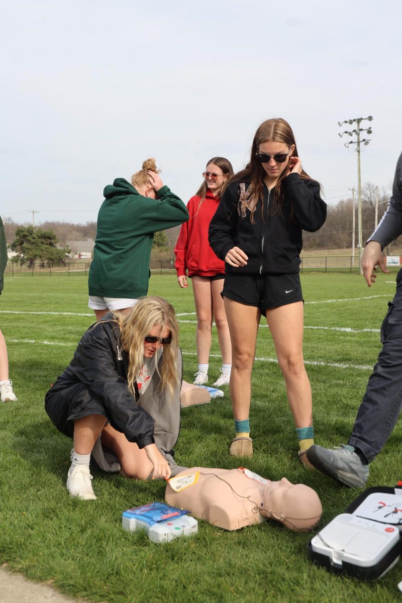 Demonstrating, senior Taylor Thornburg and senior Elena Kinsman learn CPR. On April 17, the Fenton Girls Soccer team held a CPR training for the players. 