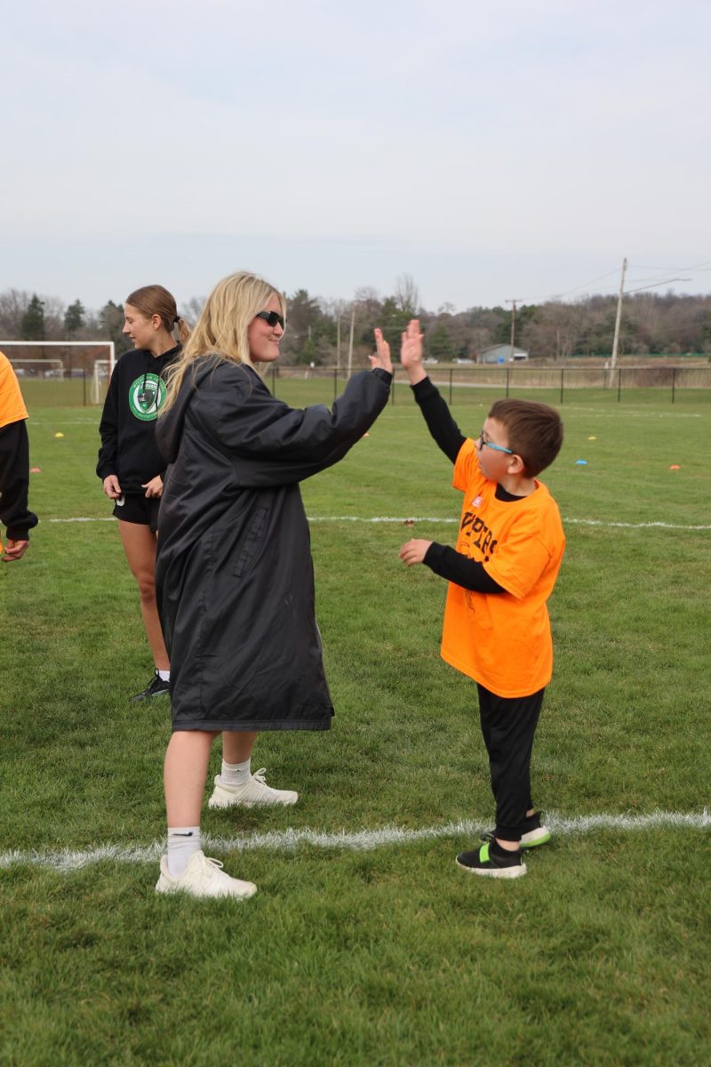 Going in for a high five, senior Taylor Thornburg gets to know her viper partner. On April. 17, the Fenton varsity girls soccer team held a practice with the Vipers soccer team at Fenton High School.
