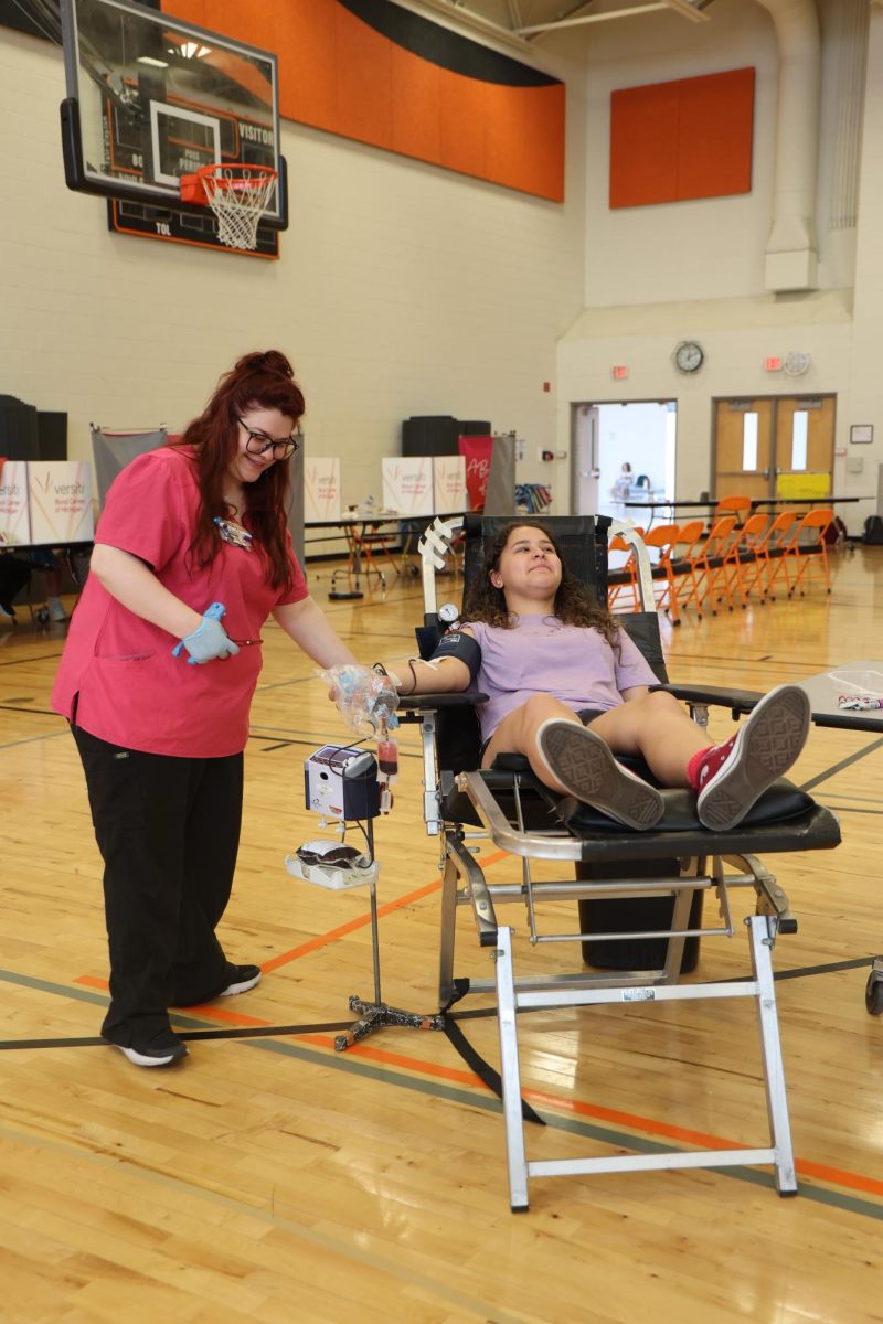Looking away, sophomore Izzy Ice donates blood. On April 25, NHS held their annual blood drive in the aux gym.