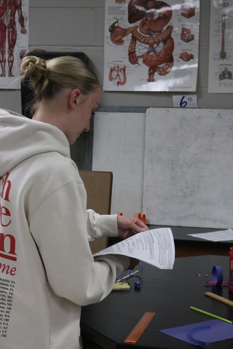 Reading, freshman Aubrey Baize participates in a lab. On April 17, the biology classes held a bird evolution lab. 