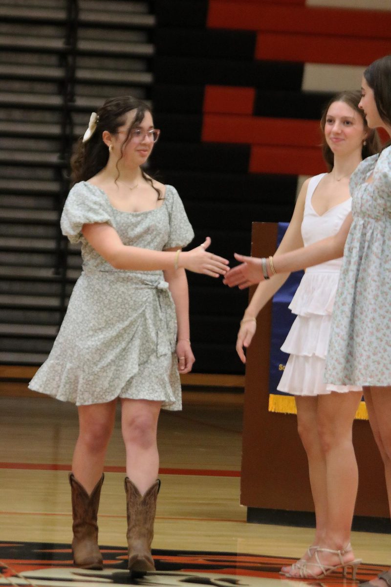 Shaking hands, sophomore Katy Smith and junior Karely Russel celebrate the induction. On April 30, the NHS gathers in the gym to welcome its new members.