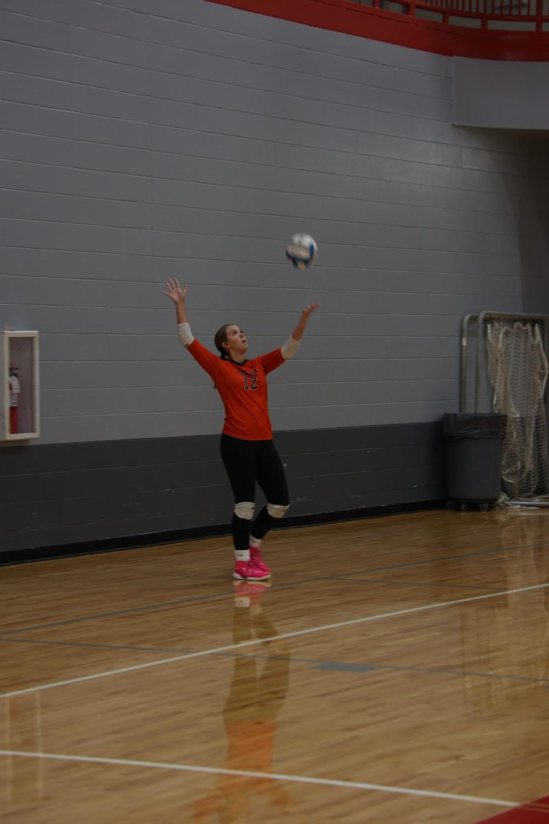 Looking, freshmen Sylvia Grasso serves the volleyball. On Sept. 4, the girls freshmen volleyball team competes against Holly High.