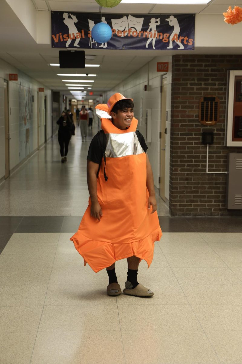 Smiling down the hallway, senior Carlos Gomez is wearing a traffic cone costume. On Sept. 19, the students participated in Orange and Black Day for Homecoming spirit week.