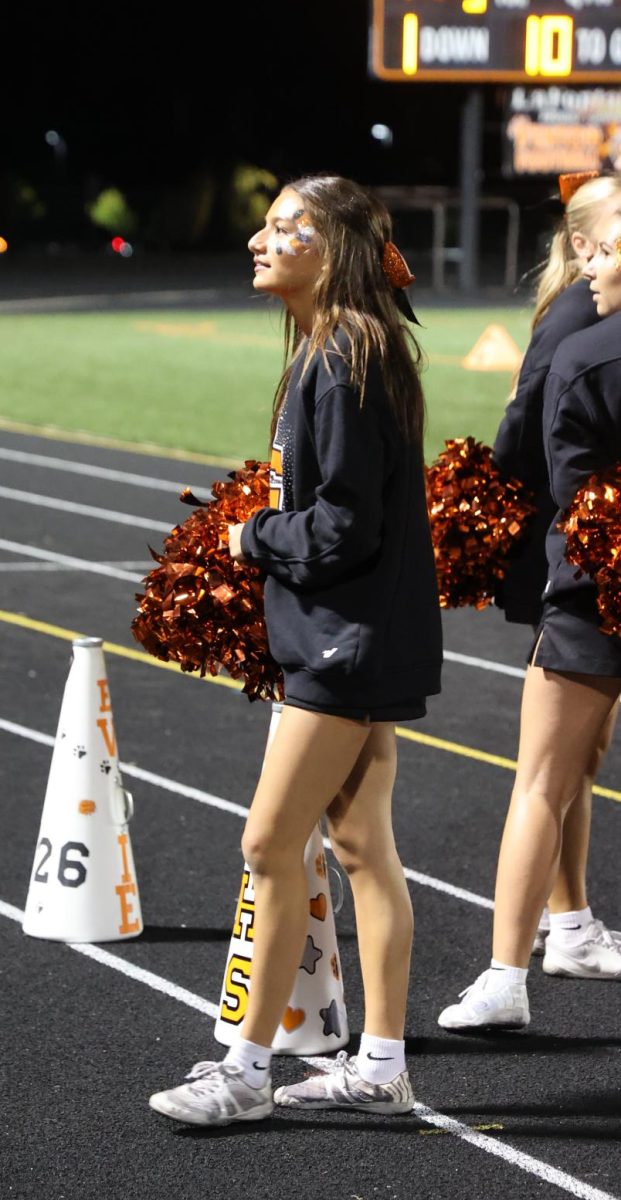 Standing on the sideline, junior Lillian Brawner gets ready to call the next cheer. On Sept.19, the varsity cheer team cheered on the sidelines of the varsity football game. 