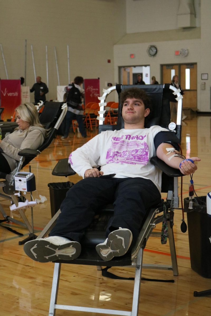 Sitting in a chair, junior Hudson Dyer donates blood. On Sept. 5, students gathered in the Auxiliary Gym to donate to the Versiti Blood Bank.