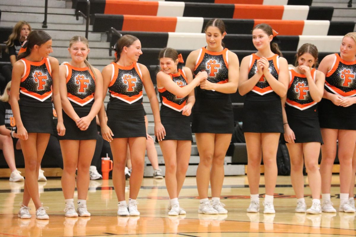 Smiling, junior Kenna Bigger laughs with her team. On Aug. 20, Fenton fall sports teams meet in the gym. 