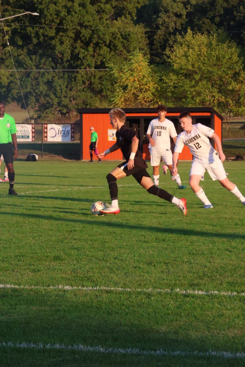 Running, junior Dakota Lawrence guards his opponent from getting the ball. On Sep. 10, the FHS varsity soccer team went up against Corunna High School.