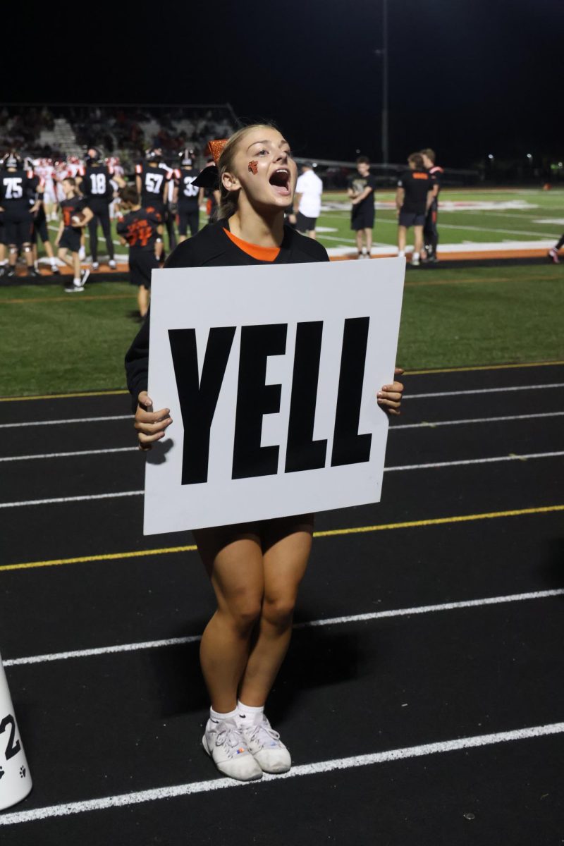 Yelling, senior Evie Metcalfe performs for the cheer team. On Sept. 19, the annual homecoming game was held.