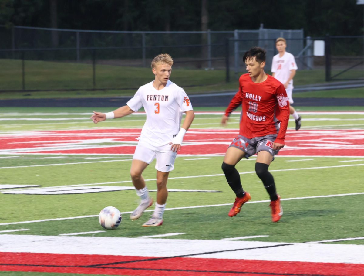 Focusing, junior Dakota Lawrence steals the ball from his opponent. On Sept. 3, the Fenton varsity soccer team won against Holly 2-1.