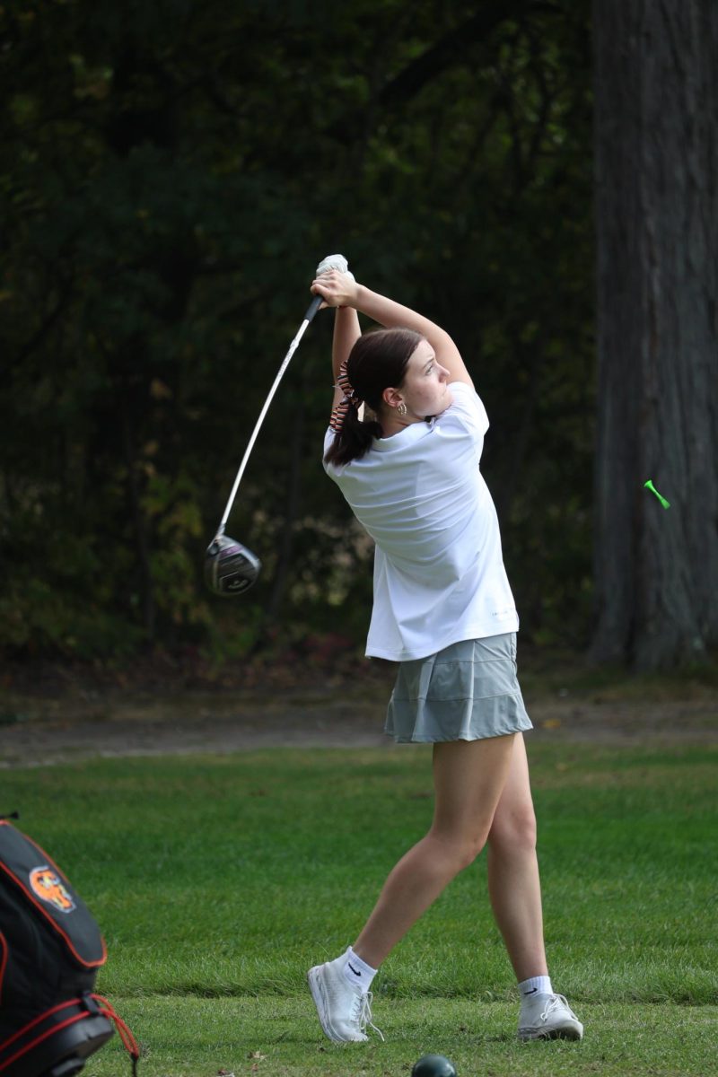 Striking the ball, junior Madeline Rhode hits her tee shot. On Sept. 18, the Fenton girls varsity golf team played Flushing at Tyrone Hills.
