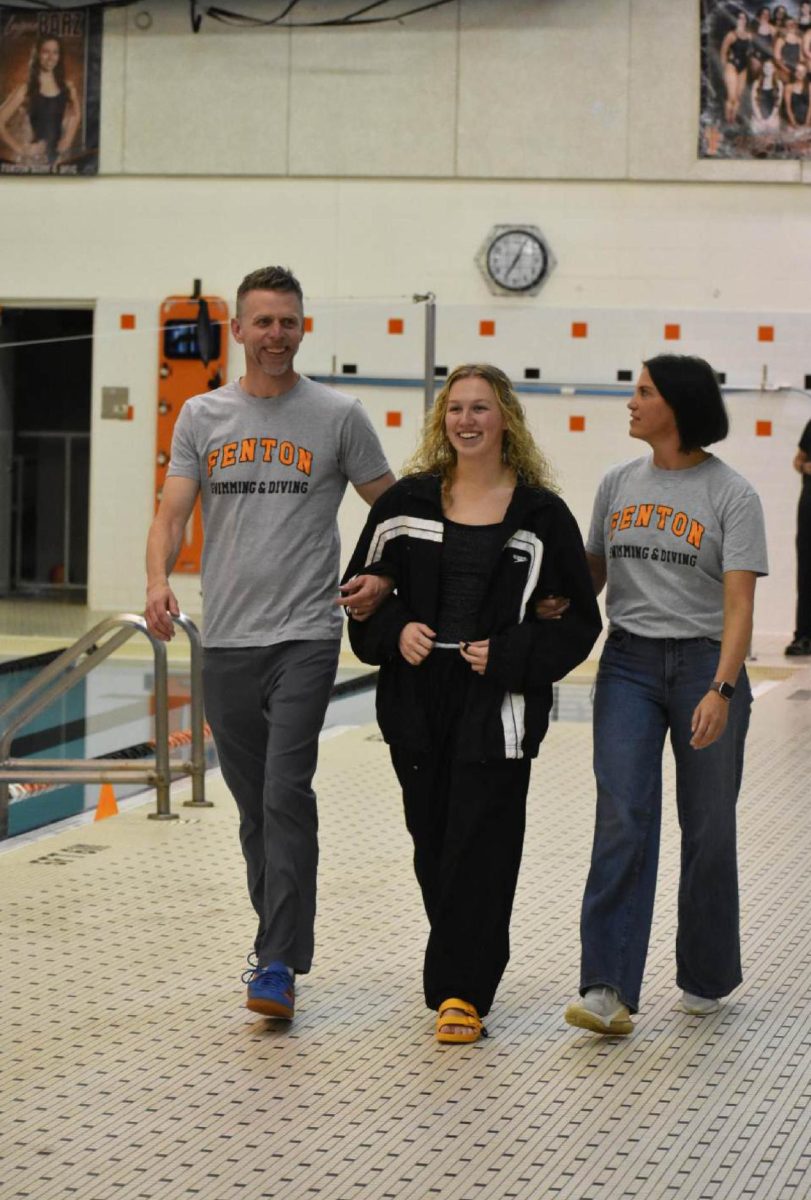 Walking with her parents, senior Josie Fries gets escorted down the pool deck. On Oct. 16, the girls swim and dive team held their senior night.