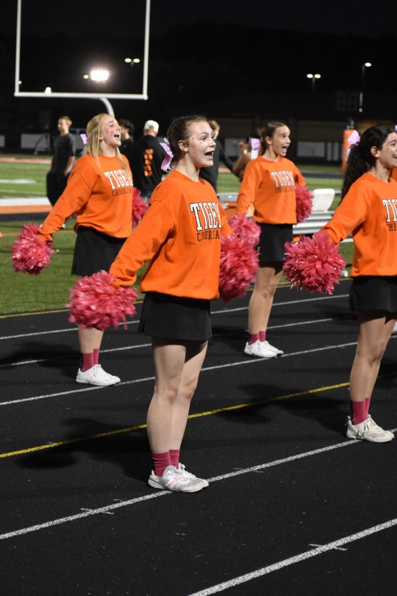 Smiling at the crowd, freshman Presley Angles cheers at the JV game. On Oct. 16, the JV cheer team rooted for Fenton vs. Goodrich.