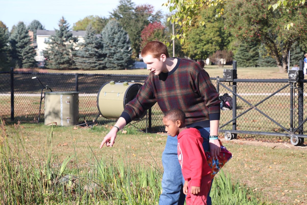 Pointing out the bugs in the pond, Senior Simon Graff participates in Pond day. On Oct. 13, FHS hosts Pond day for the elementary students to be taught about the environment by highschoolers 