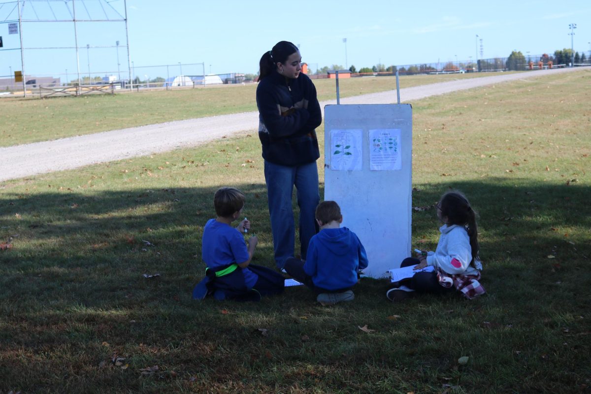 Looking down, junior Jannessa Bemman , is teaching the elementary school kids about leaves and the ecosystem. On Oct. 13 the Eco club held Pond day to teach the kids about how the environment works.