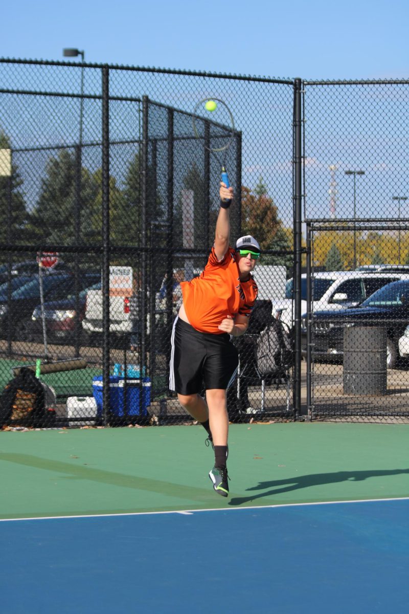 Serving the ball, senior Jonas Ritchie swings hard against his opponent from Brandon High.  On Sept. 23 boys varsity tennis won against the Brandon Blackhawks.