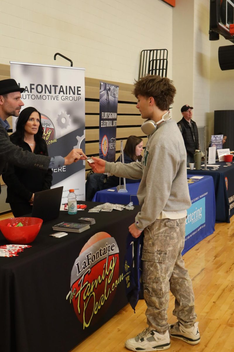 Taking a business card, Senior Calvin Szafranski is talking to the LaFontaine Automotive group. On Nov. 6, the junior and senior class talked to different groups for careers.